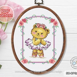 May include: Cross stitch pattern featuring a cute teddy bear dressed as a ballerina with a pink flower crown. The pattern is framed with a purple and green border and pink roses.