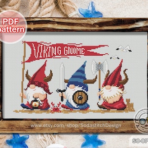 May include: Cross stitch pattern featuring three gnomes dressed as Vikings. The gnomes are holding a sword, an axe, and a lantern. The banner above them reads "Viking Gnome".