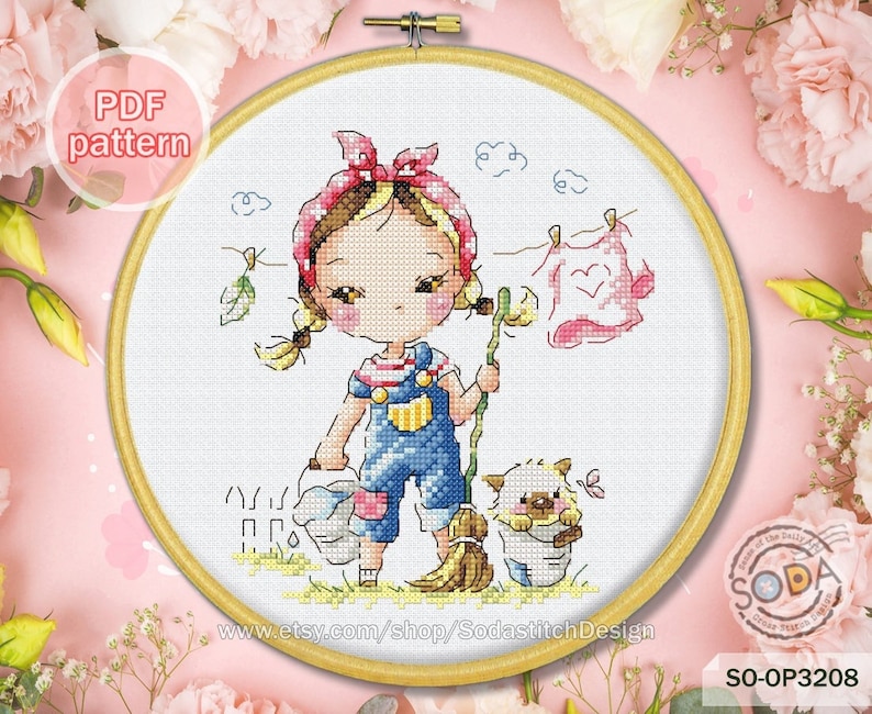 Op de afbeelding: Een kruissteekpatroon met een cartoonmeisje met een rode bandana, een blauwe overall en een bezem, die bladeren veegt. Ze houdt een emmer vast met een roze bloem en een blauwe vlinder. Een kleine witte hond zit in een emmer naast haar. Het patroon is in een ronde borduurring met een witte achtergrond.