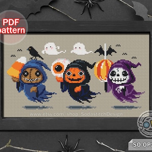 May include: Cross stitch pattern featuring three cute Halloween characters: a blue ghost holding candy corn, a black ghost with a pumpkin face, and a purple ghost with a skull face. The pattern includes the text "www.etsy.com/shop/SodastitchDesign" and the code "SO-OP2181".