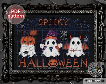 May include: A cross-stitch pattern featuring three ghosts dressed as a pumpkin, a witch, and a devil. The ghosts are in front of a black gate with the words "Spooky Halloween" above them. The pattern is in black and white.
