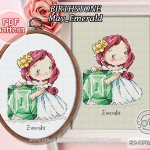 May include: Cross stitch pattern featuring a cartoon girl with red hair holding a large green emerald gemstone. The pattern is titled "May_Emerald" and is part of a birthstone collection. The text "PDF pattern" is in a red box at the top left of the image.