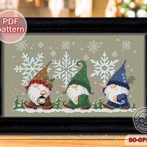 Puede incluir: Patrón de punto de cruz con tres gnomos que llevan sombreros y sostienen copos de nieve. Los gnomos están de pie en un paisaje nevado con una linterna y pinos. El patrón se titula "SO-OP2190".