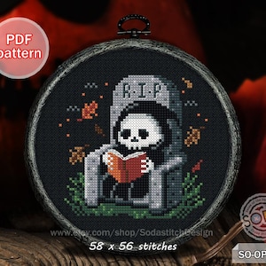 May include: A cross-stitch pattern featuring a Grim Reaper reading a book in front of a tombstone. The design is set in a black hoop with a dark frame. The text "PDF pattern" is in a red circle. The design measures 58 x 56 stitches.