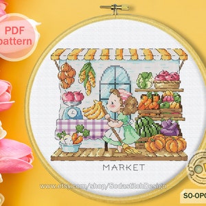 May include: A cross-stitch pattern of a girl shopping at a market. The market has a striped awning and is filled with colorful fruits and vegetables. The girl is holding a broom and wearing a green dress. The text "MARKET" is below the market.