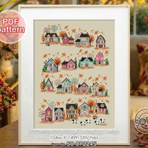 May include: Framed cross-stitch pattern depicting a village scene with colourful houses and autumn leaves. The artwork includes the text "PDF pattern" and the Etsy shop URL. The design measures 104 stitches wide by 149 stitches high.