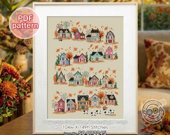 May include: Framed cross-stitch pattern featuring a village scene with colorful houses and autumn foliage. The artwork includes the text "PDF pattern" and the Etsy shop URL. The design measures 104 stitches wide by 149 stitches high.