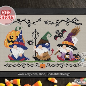 Puede incluir: Patrón de punto de cruz con tres gnomos vestidos con trajes de Halloween. El gnomo de la izquierda lleva un sombrero de calabaza, el gnomo del medio lleva un sombrero de bruja y el gnomo de la derecha lleva un sombrero de mago. El patrón incluye un murciélago, una araña, un fantasma, una escoba, una linterna y una calabaza. El patrón se titula "SO-OP284".