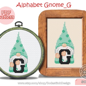 May include: Cross-stitch patterns of a gnome holding the letter "G". The gnome has a green hat with polka dots, a white beard, and a black letter "G". One is framed in a wooden frame, the other in a round hoop. Text: Alphabet Gnome_G, PDF pattern.