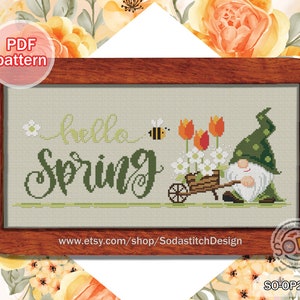 May include: Cross-stitch design with the words "hello SPRING" in green script, a bee, and a gnome with a wheelbarrow of flowers, including tulips and daisies. The text "PDF pattern" is in the upper left corner. The design is framed in a wooden border.