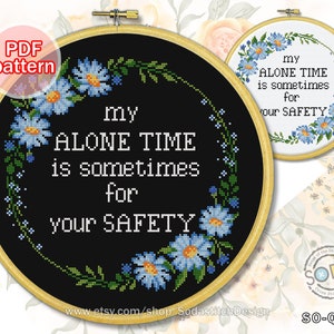 以下が含まれることがあります： 花柄の縁取りが施された白黒のクロスステッチパターン。テキストには「私の独り時間は、あなたの安全のためです」と書いてあります。