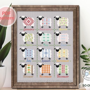 May include: A cross-stitch pattern featuring 12 sheep, each with a different patterned sweater representing a month of the year. The sheep are arranged in a grid with the months labeled below each sheep. The pattern is framed in a brown wooden frame.