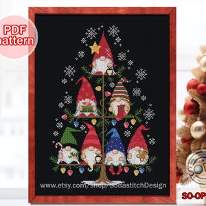 Puede incluir: Un patrón de punto de cruz con un árbol de Navidad con siete gnomos que llevan sombreros rojos, azules, verdes y amarillos. El árbol está decorado con copos de nieve, luces y adornos. El patrón está disponible para descargar en PDF. El texto "SO-OP2279" está en la esquina inferior derecha de la imagen.