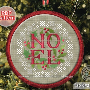 May include: A red and white Christmas ornament with a cross-stitch design that reads "NO ELVES". The ornament is framed in a red wooden hoop and is hanging on a Christmas tree.