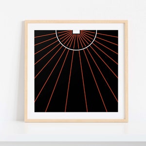 May include: Framed abstract art print featuring a black background with orange radiating lines emanating from a white semi-circle. The artwork is in a light wood frame, displayed against a white wall.
