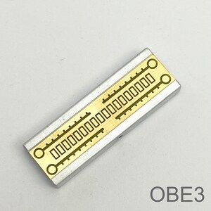 Peut inclure: Un composant &eacute;lectronique argent&eacute; et dor&eacute; avec une s&eacute;rie de d&eacute;coupes rectangulaires et circulaires. Le composant est &eacute;tiquet&eacute; "OBE3".
