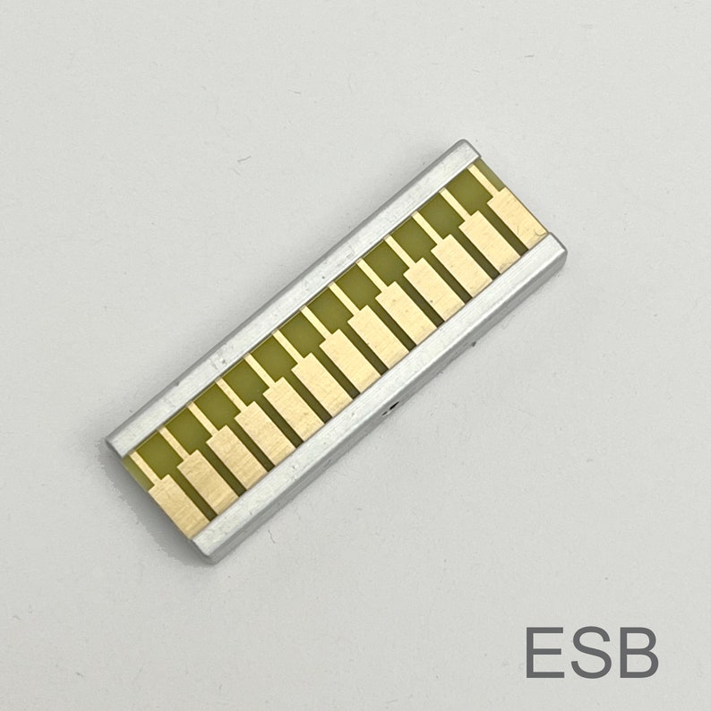 Peut inclure: Un composant &eacute;lectronique rectangulaire de couleur argent&eacute;e avec une s&eacute;rie de plaquettes rectangulaires dor&eacute;es. Le composant est &eacute;tiquet&eacute; "ESB".