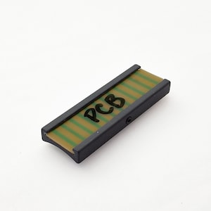 Pode incluir: Uma placa de circuito impresso (PCB) retangular com um padrão de listras verdes e bege. A placa é emoldurada em preto e tem as letras "PCB" escritas com um marcador preto. O item está em um fundo branco.