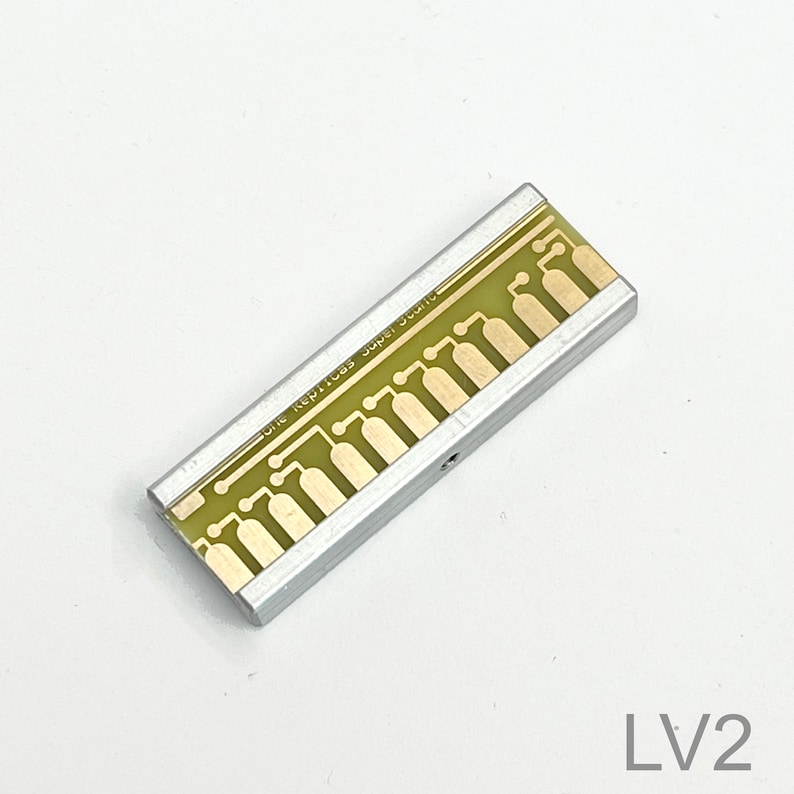 Peut inclure: Une carte de circuit imprim&eacute; argent&eacute;e avec un circuit imprim&eacute; vert et le texte "ONE KEP1085 SUPER SOUND" dessus.