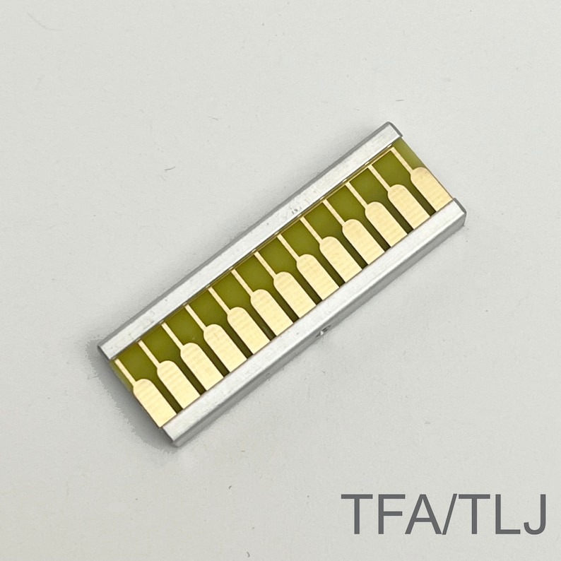 Peut inclure: Un composant &eacute;lectronique argent&eacute; et dor&eacute; avec 14 contacts dor&eacute;s. Le composant est &eacute;tiquet&eacute; "TFA/TLJ".