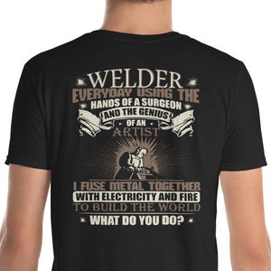 May include: Black t-shirt with a brown graphic design that reads "Welder Everyday using the hands of a surgeon and the genius of an artist. I fuse metal together with electricity and fire to build the world. What do you do?"