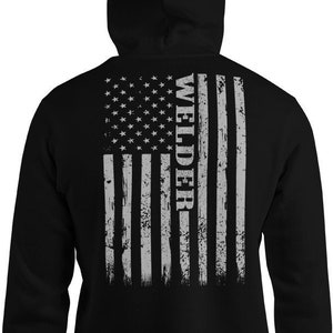 May include: Black hooded sweatshirt with a distressed American flag design on the back. The flag is gray and white with the word "WELDER" vertically down the right side.