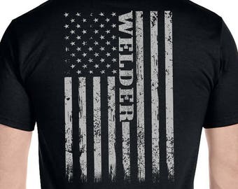 May include: Black t-shirt with a distressed American flag design and the word "WELDER" printed vertically on the flag.