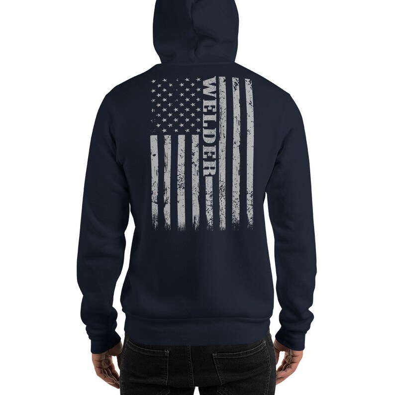 May include: Navy blue hooded sweatshirt with a distressed American flag design on the back. The flag is gray and white with the word "WELDER" vertically down the right side.