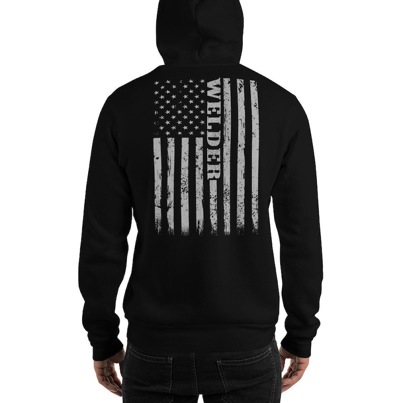 May include: Black hooded sweatshirt with a distressed American flag design on the back. The flag is gray and white with the word "WELDER" vertically down the right side.
