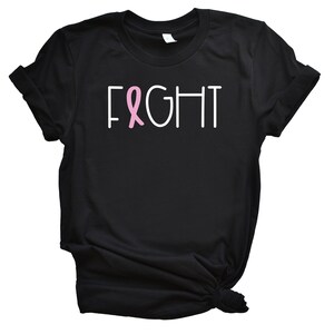 May include: Black t-shirt with the word "FIGHT" in white text and a pink ribbon.