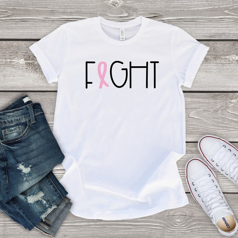 May include: White t-shirt with the word "FIGHT" in black letters and a pink ribbon in the middle of the word.