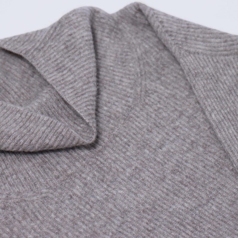 May include: Close-up of a gray ribbed knit sweater with a cowl neck.