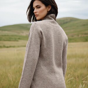 May include: A woman wearing a light brown ribbed turtleneck sweater. The sweater has a relaxed fit and long sleeves.
