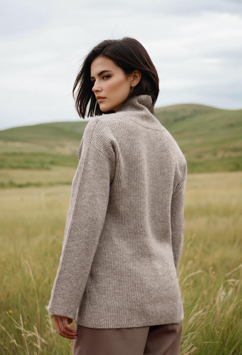 May include: A woman wearing a light brown ribbed turtleneck sweater. The sweater has a relaxed fit and long sleeves.