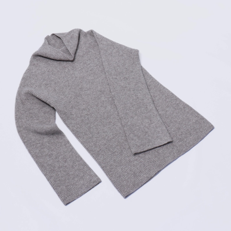 May include: A gray ribbed knit sweater with a cowl neck.