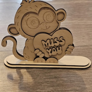 Könnte beinhalten: Holzschnitt eines Affen, der ein Herz mit der Aufschrift "Miss You" hält.