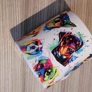 May include: White ceramic mug with a colorful watercolor pattern of different dog breeds. The dogs are painted in shades of blue, green, orange, red, and purple.