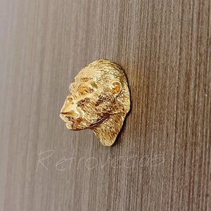 May include: Gold-coloured metal door knob with a detailed gorilla head design.
