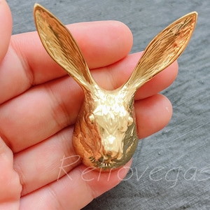 Peut inclure: Une sculpture de tête de lapin de couleur dorée avec des détails précis. La sculpture est en métal et a une apparence réaliste.