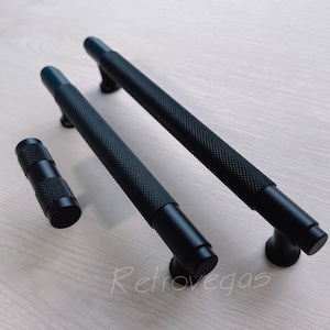 May include: Three black metal cabinet pulls with a textured finish. The pulls are in various sizes and shapes.