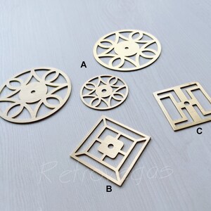 Könnte beinhalten: Fünf dekorative Messingstücke mit filigranen Designs. Die Stücke sind in Form von Kreisen und Quadraten. Die Stücke sind mit A, B und C gekennzeichnet.