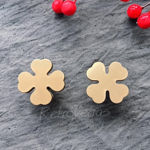 Könnte beinhalten: Zwei goldfarbene Schubladengriffe in Form eines vierblättrigen Kleeblatts.