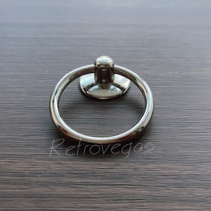 Peut inclure: Une poignée de porte de placard en argent avec une base ronde.