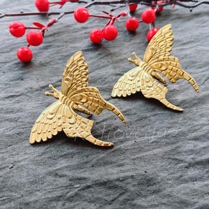 Op de afbeelding: Twee gouden vlinder oorringen met ingewikkelde details. De oorringen zijn van een delicaat en elegant ontwerp.