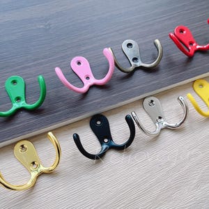 Puede incluir: Un conjunto de diez perchas de doble gancho en varios colores, incluyendo dorado, negro, plateado, verde, rosa y amarillo. Las perchas están hechas de metal y tienen un diseño simple y clásico.