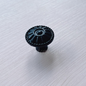 May include: Black cabinet knob with a decorative floral design.