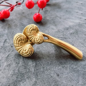 May include: Gold-toned facial roller with two textured, leaf-shaped heads and a curved handle.