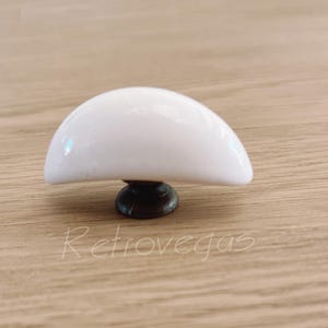 Op de afbeelding: Witte keramische halfronde kastknop met een donkerbruine metalen basis.