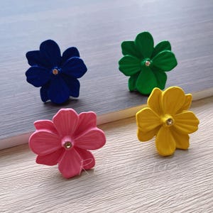 Può includere: Quattro tiretti per cassetti a forma di fiore con un centro di strass. I tiretti sono di colore blu, verde, rosa e giallo.