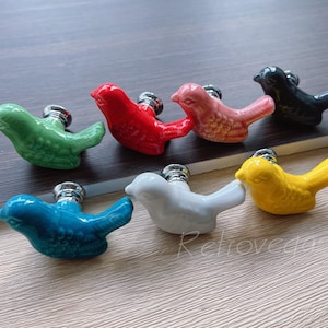 May include: Set of ten ceramic bird drawer pulls in various colours, including green, red, pink, yellow, blue, black, and white. Each pull features a bird design with a metal knob.